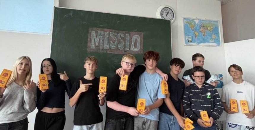 Schülerinnen und Schüler mit Produkten vor einer Tafel mit der Aufschrift "MISSIO"